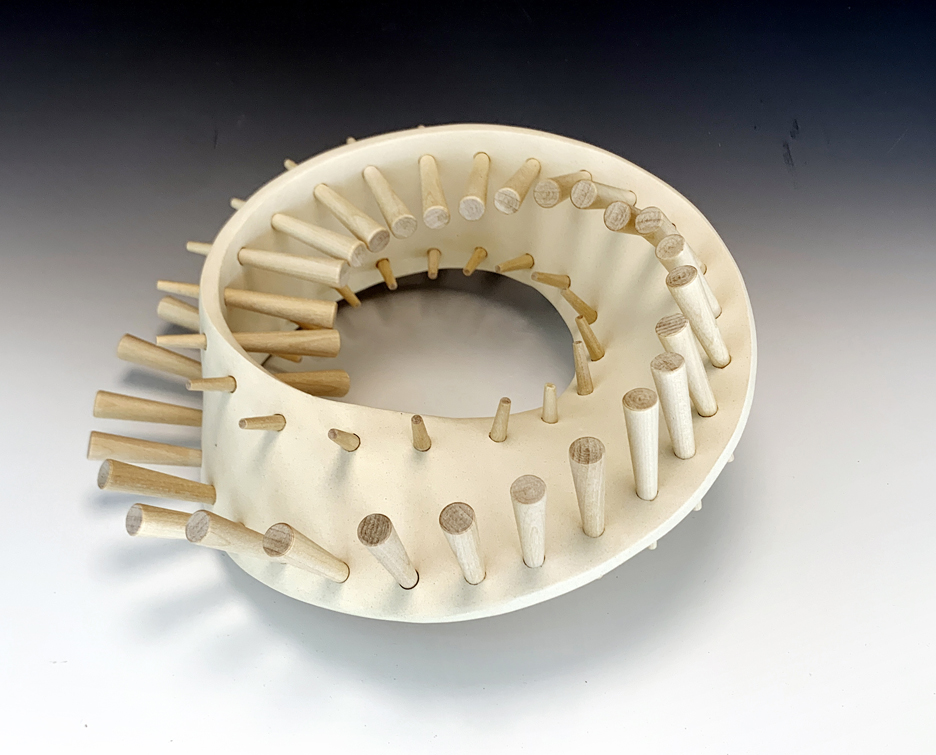 Ceramic sculpture of a Mobius band with wooden pegs.